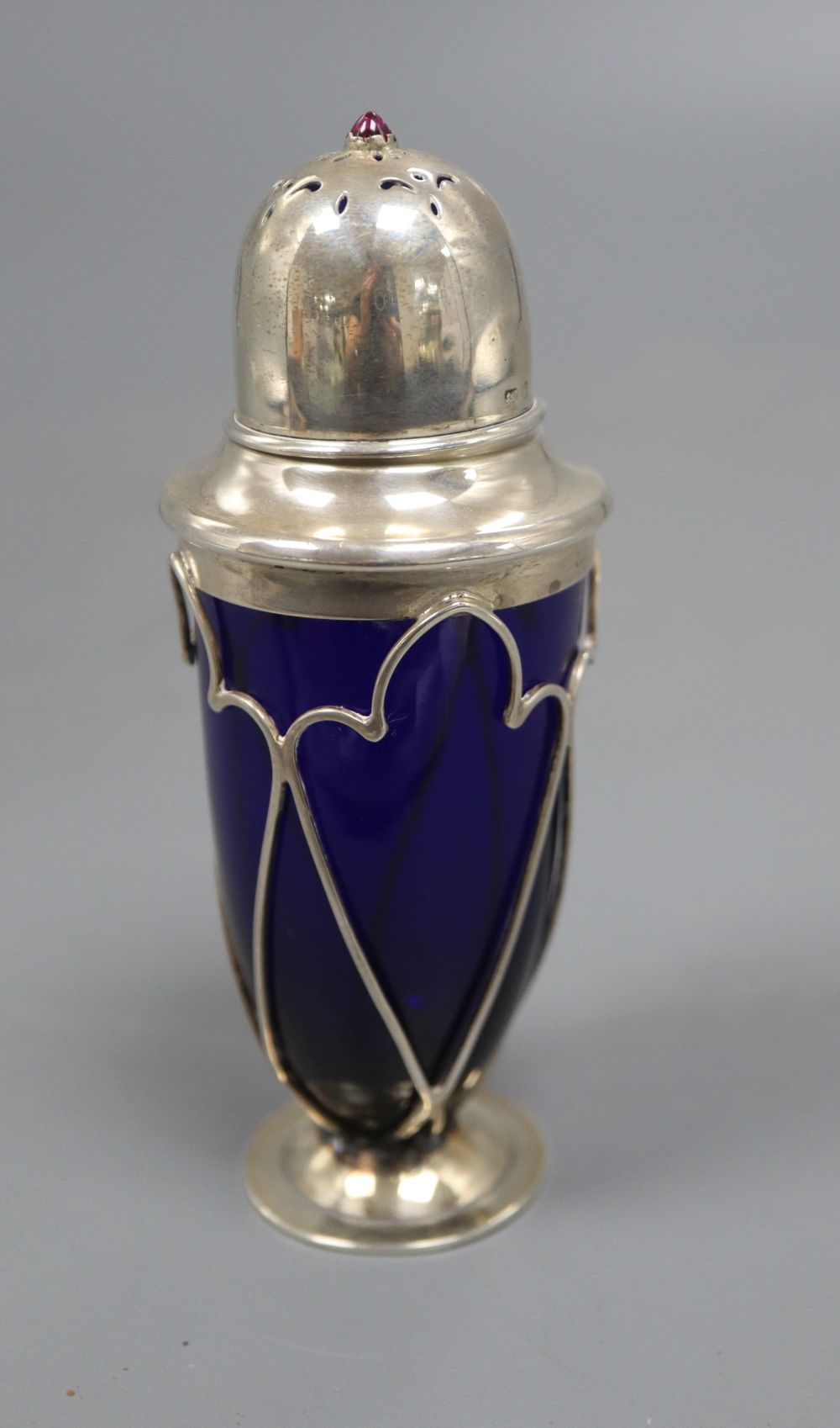 An Edwardian Arts and Crafts silver and gem set mounted blue glass sugar shaker, no makers mark, 12.3cm.